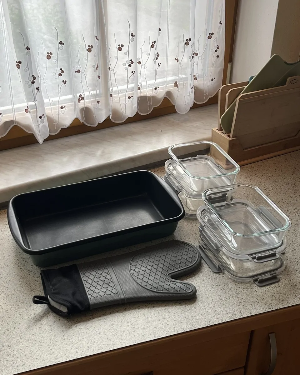 Workspace showing a big baking dish, 4 meal prep containers and an oven glove